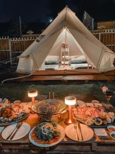 einen Tisch mit Teller mit Lebensmitteln und einem Zelt in der Unterkunft MUINE SUN & SEA BEACH ( BOUTIQUE RESORT & GLAMPING) in Mui Ne