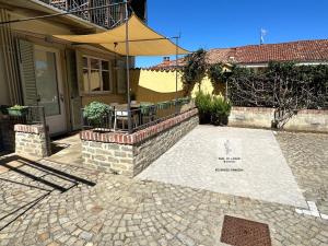a patio with a table and an umbrella in front of a house at Made in Langhe Apartment in La Morra