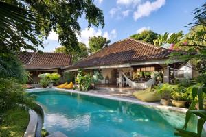 a swimming pool in front of a house with a hammock at Villa Matahari in Kerobokan