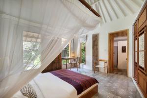 a bedroom with a canopy bed and a desk at Villa Maia in Kerobokan