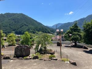 un parque con un árbol y rocas y montañas en 癒しのwonderland 泉, en Gujō