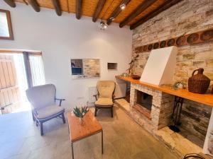 sala de estar con 2 sillas y chimenea de piedra en Traditional Village Pool Paradise Family Apartment, en Skarinou