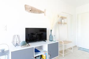 a living room with a tv on a white wall at Appartement Neuf 4 étoiles - Sunset Lodge, Narbonne Plage in Narbonne