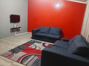 a living room with a couch and a red wall at Umtentweni, Seaview Unit Alpero in Port Shepstone