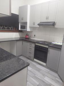 a kitchen with white cabinets and a black stove top oven at Umtentweni, Seaview Unit Alpero in Port Shepstone