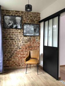 una silla en una habitación con una pared de ladrillo en Gîte la Maison Rouge Béthune, en Béthune