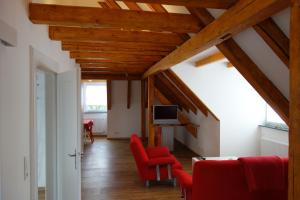 a living room with wooden ceilings and red chairs at Ferienwohnung & Wellness in Bad Kissingen