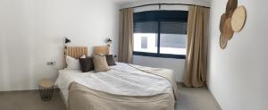 um quarto com uma cama com lençóis brancos e uma janela em villamar III em San Pedro del Pinatar