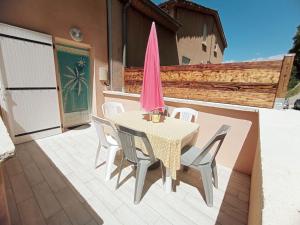 a table with chairs and a pink umbrella on a patio at Appartement neuf tout confort in Aubenas