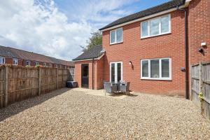 a red brick house with a wooden fence and a patio at Elegant Design 75" Smart Tv Long Stay Welcome in Norwich