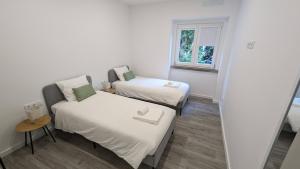Habitación pequeña con 2 camas y ventana en Golligo Apartments, en Sintra