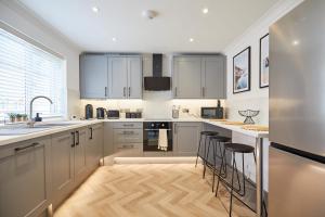 a kitchen with white cabinets and bar stools at Elegant Design 75" Smart Tv Long Stay Welcome in Norwich