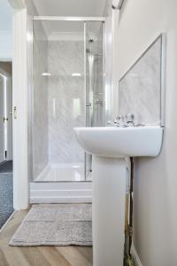 a white bathroom with a sink and a shower at Freshly Refurbished Open-plan Dining & Kitchen in Norwich