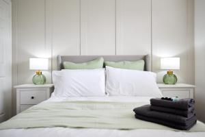 1 cama blanca con almohadas blancas y 2 lámparas en Elegant Design 75" Smart Tv Long Stay Welcome en Norwich