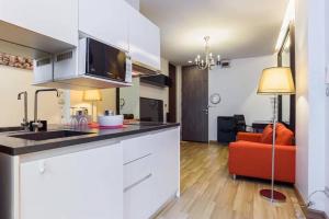 a kitchen with white cabinets and a red couch at Vinn condo in Amphoe Phra Khanong