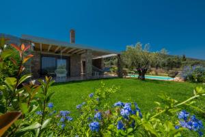 ein Haus mit einem Hof mit blauen Blumen in der Unterkunft Avista Private Resort in Vourvourou