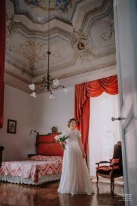Una mujer con un vestido de novia parada frente a una cama en Le Foglie Di Acanto, en Lucera