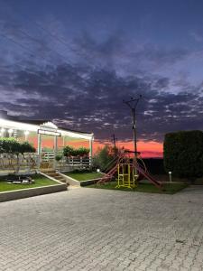 a playground in a park with a cloudy sky at Monte Rei Hotel in Lushnjë