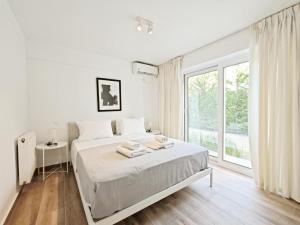 a white bedroom with a bed and a large window at Kalipsous Apartments by Verde Apartments in Athens