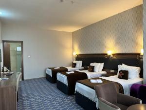 a hotel room with three beds in a room at Banoj Hotel in Erbil