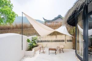 patio z namiotem i krzesłami oraz budynkiem w obiekcie Moganshan 107 Courtyard B&B w mieście Deqing