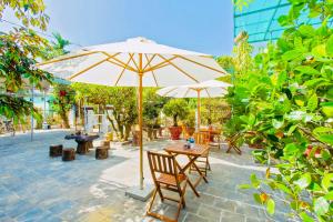 un patio con mesa y sombrilla en Pebble Homestay en Hoi An