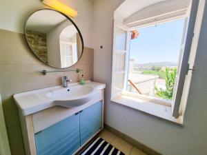 baño con lavabo, espejo y ventana en Village Charm with Pool Apartment at Skarinou, en Skarinou