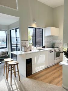 a kitchen with white cabinets and a table and chairs at Ultimate Location Luxury Retreat - 2 bedrooms 2 bathrooms in Mount Maunganui