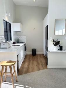 a kitchen with white counters and a wooden stool at Ultimate Location Luxury Retreat - 2 bedrooms 2 bathrooms in Mount Maunganui