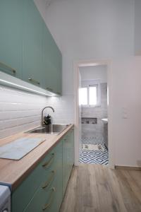 a kitchen with blue cabinets and a sink and a bathroom at Piraiki Coastal Accommodation in Piraeus