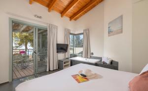um quarto com uma cama, uma televisão e uma varanda em Vered Hagalil Holiday Village Hotel em Chorazim
