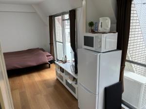 een kamer met een koelkast en een magnetron. bij Guest House ZEN HAKATA Ohori Park in Fukuoka