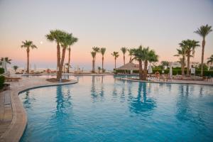 a large swimming pool with palm trees in a resort at Safir Sharm Waterfalls Resort in Sharm El Sheikh