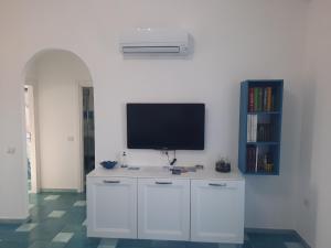 een woonkamer met een tv aan een witte muur bij Villa la Torre Maestrale in Torre Dei Corsari