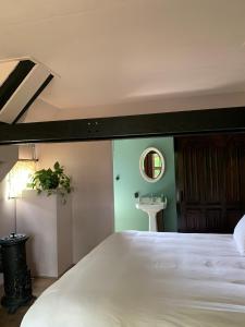 ein Schlafzimmer mit einem großen weißen Bett und einem Waschbecken in der Unterkunft Bed and Breakfast Bakrust, met privé sauna Putten in Putten