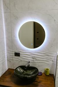 a bathroom with a sink and a round mirror at Vila Pllaha in Korçë