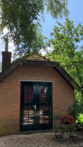 a small brick building with a black door and a table at Bed and Breakfast Bakrust, met privé sauna Putten in Putten