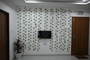 Un televisor en una pared con hojas verdes. en Staeg 102-1Bhk Furnished Apt, en Indore