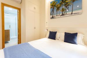 a bedroom with a white bed with blue pillows at Holidays2Malaga Victoria 40 Quiet & Central in Málaga