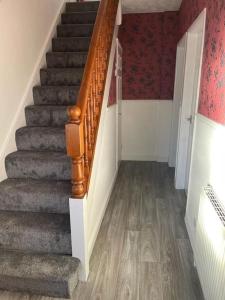 a stairway with a wooden railing and a stair case at Lovely 3 bedroom house with off street parking in Thornton