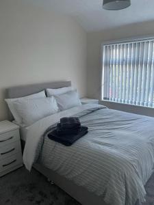 a white bedroom with a bed and a window at Lovely 3 bedroom house with off street parking in Thornton
