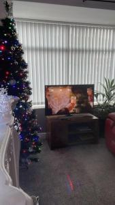 a living room with a christmas tree and a tv at Lovely 3 bedroom house with off street parking in Thornton