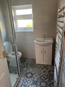 een badkamer met een wastafel, een toilet en een raam bij Lovely 3 bedroom house with off street parking in Thornton