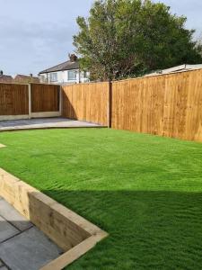 a backyard with a wooden fence and a green lawn at Lovely 3 bedroom house with off street parking in Thornton