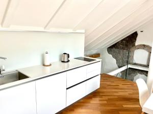 a kitchen with white cabinets and a stone wall at Historic Rooms and Apartments in the City Centre of Bolzano in Bolzano