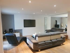 een woonkamer met een bank en een flatscreen-tv bij Luxury Villa - LA JACHERE in Épinay-sous-Sénart