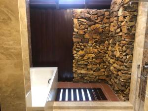 a stone wall in a bathroom with a shower at Langkawi Lagoon Water Villa VIP in Pantai Cenang