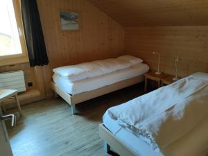 a bedroom with two beds in a wooden room at Hotel Furka in Oberwald