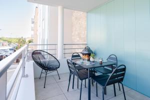 a patio with a table and chairs on a balcony at Appartement Neuf 4 étoiles - Sunset Lodge, Narbonne Plage in Narbonne