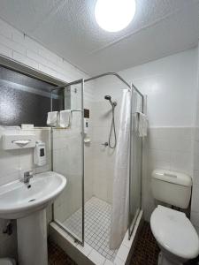 a bathroom with a shower and a toilet and a sink at Marco Polo Motor Inn Sydney in Sydney